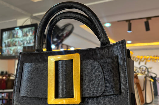 Black handbag with a gold buckle in a store setting